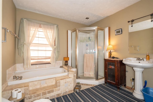 full bath with a textured ceiling, a stall shower, and a bath