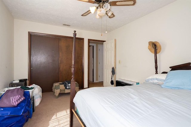 bedroom featuring visible vents, a ceiling fan, a textured ceiling, carpet floors, and a closet