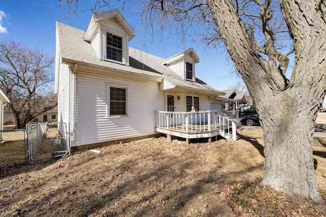 rear view of house with a deck, a shingled roof, fence, and a gate