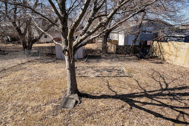 view of yard with a fenced backyard, a storage unit, and an outbuilding