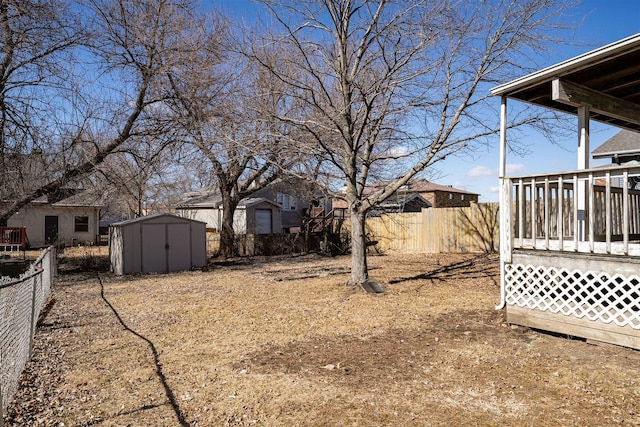 view of yard featuring an outbuilding, a fenced backyard, a wooden deck, and a storage shed