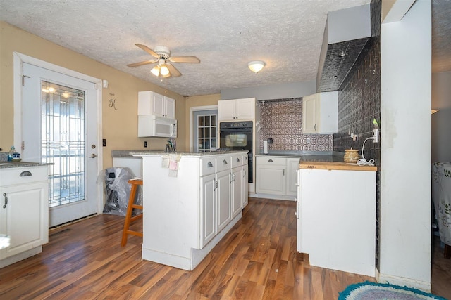 kitchen with dark wood-style flooring, white cabinets, and white microwave