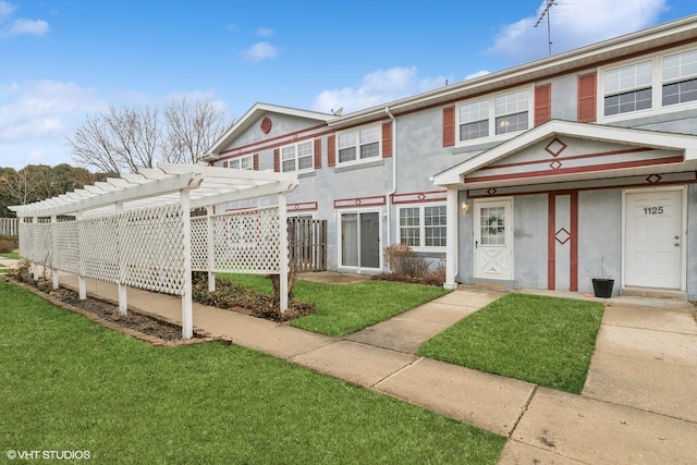 townhome / multi-family property featuring stucco siding, a front lawn, and a pergola