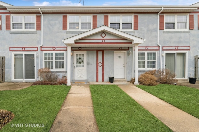 townhome / multi-family property with a front yard and stucco siding