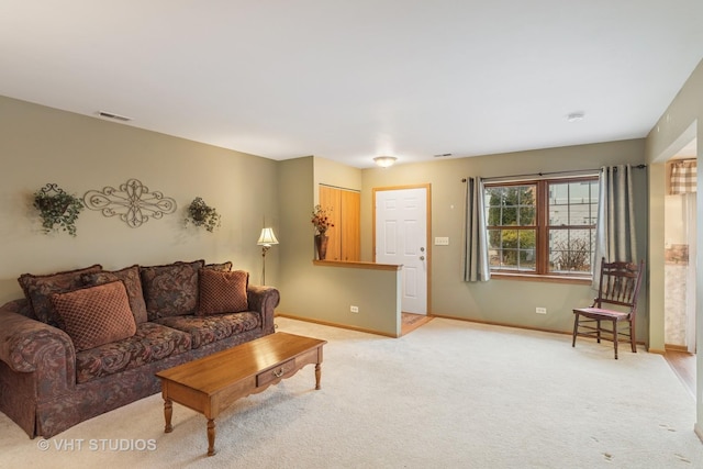 living area featuring visible vents, light carpet, and baseboards