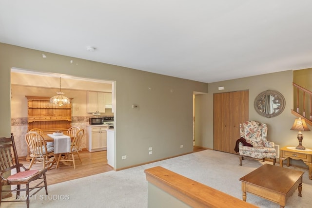 living area with baseboards, a chandelier, and light colored carpet