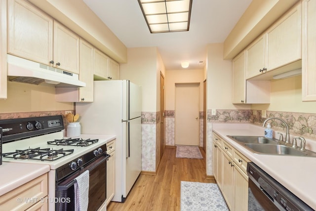 kitchen featuring light wood finished floors, gas stove, a sink, under cabinet range hood, and dishwashing machine