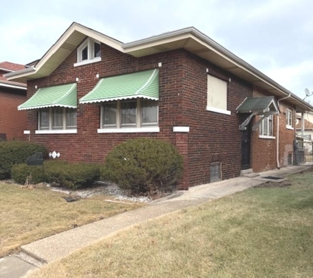 view of side of home featuring a lawn and brick siding