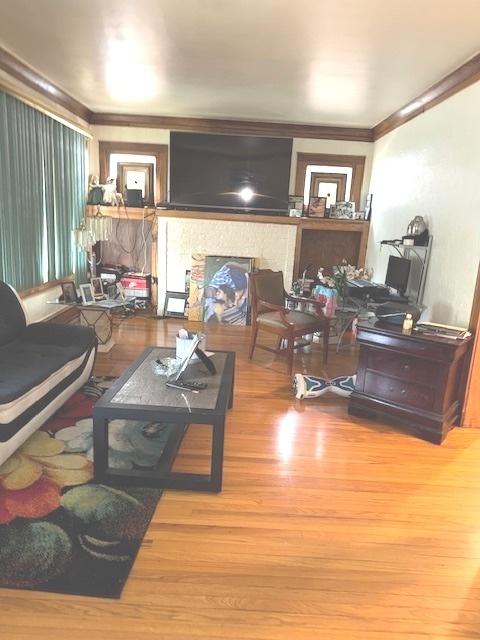 living room featuring crown molding, a fireplace, and wood finished floors