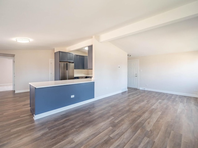 interior space featuring vaulted ceiling with beams, dark wood-type flooring, and baseboards