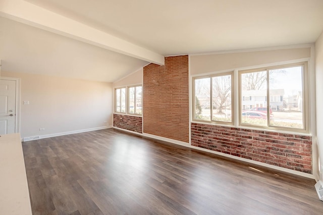 unfurnished living room with vaulted ceiling with beams, dark wood-style floors, brick wall, and baseboards