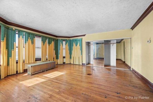 interior space featuring radiator, wood-type flooring, a textured ceiling, and crown molding