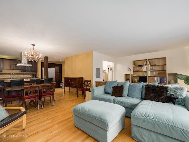 living room with light wood-type flooring, electric panel, and a notable chandelier