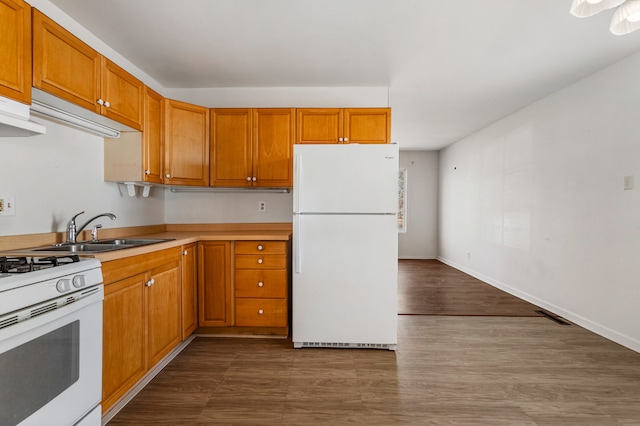 kitchen with visible vents, a sink, white appliances, brown cabinetry, and light countertops