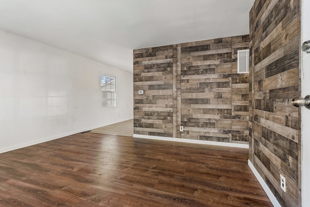 empty room featuring visible vents, baseboards, and wood finished floors