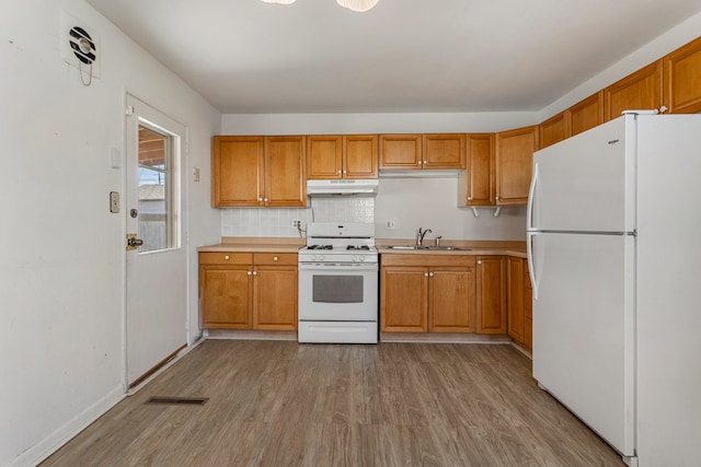 kitchen with visible vents, under cabinet range hood, a sink, white appliances, and light wood-style floors