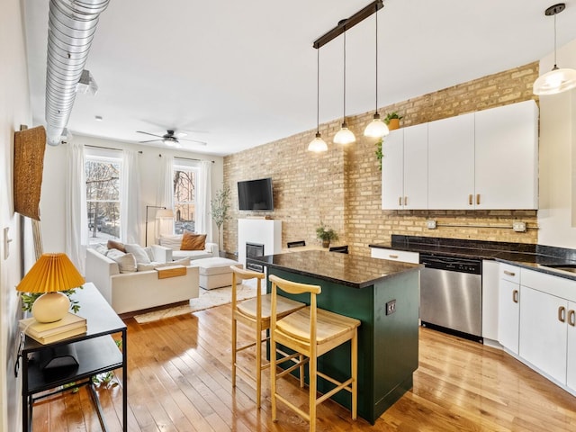 kitchen with light wood-type flooring, dark countertops, a center island, and stainless steel dishwasher