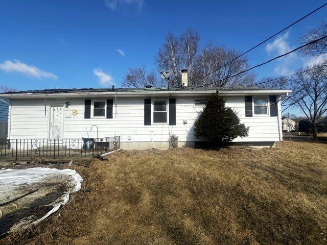 rear view of house with a chimney and fence