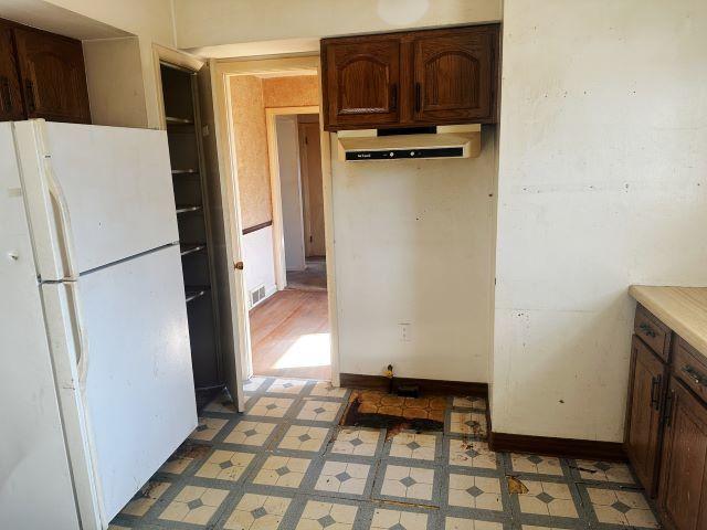 kitchen featuring freestanding refrigerator, light countertops, under cabinet range hood, and light floors