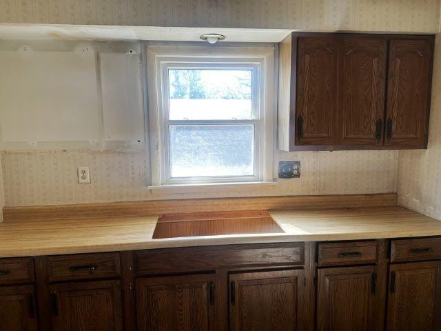 kitchen featuring cooktop, light countertops, and wallpapered walls