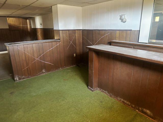 bar with a bar, wooden walls, and a paneled ceiling