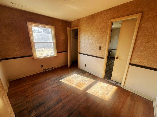 unfurnished bedroom with wood finished floors and visible vents