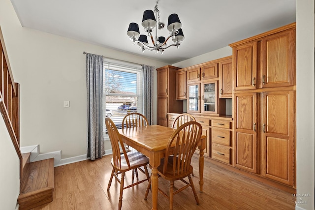 dining room featuring baseboards, stairway, light wood-style flooring, and a notable chandelier