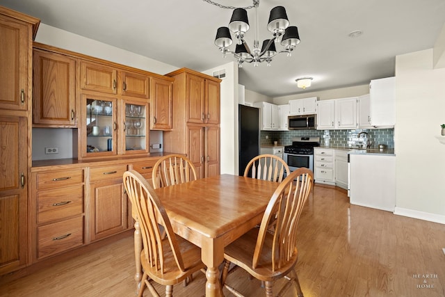 dining area with light wood-type flooring, visible vents, and a notable chandelier