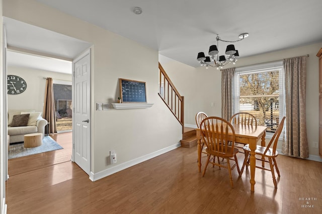 dining area featuring a chandelier, wood finished floors, baseboards, and stairs