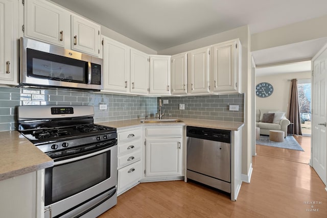 kitchen featuring a sink, white cabinetry, light countertops, appliances with stainless steel finishes, and light wood-type flooring