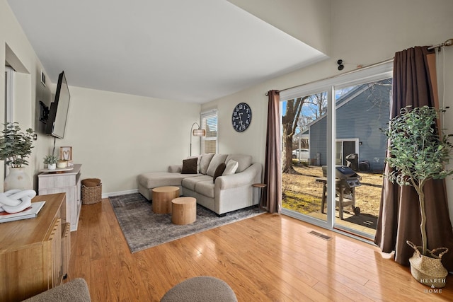 living room featuring baseboards, visible vents, and light wood finished floors