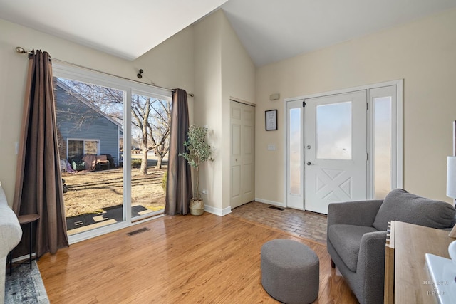 interior space featuring light wood-style floors, visible vents, vaulted ceiling, and baseboards