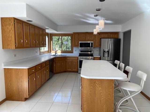 kitchen featuring appliances with stainless steel finishes, brown cabinetry, and light countertops