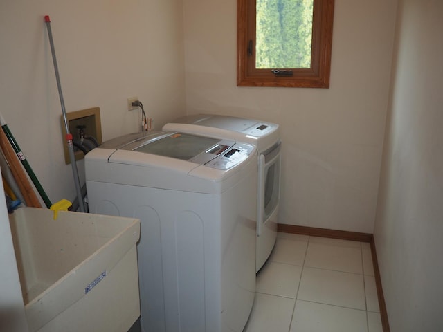 clothes washing area with light tile patterned floors, laundry area, a sink, baseboards, and independent washer and dryer