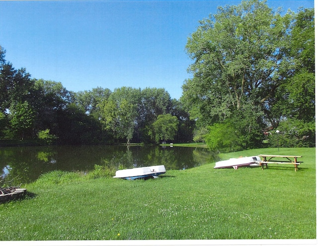 view of dock with a water view and a lawn