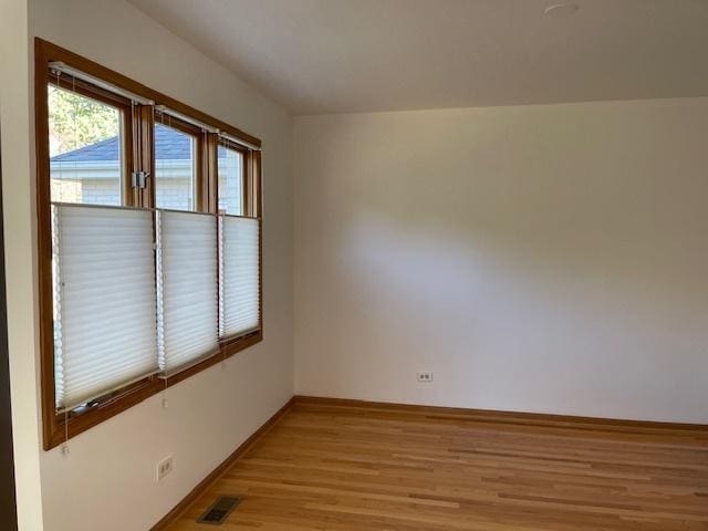 spare room with visible vents, light wood-style flooring, and baseboards