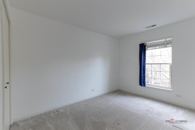 spare room featuring carpet flooring, visible vents, and baseboards