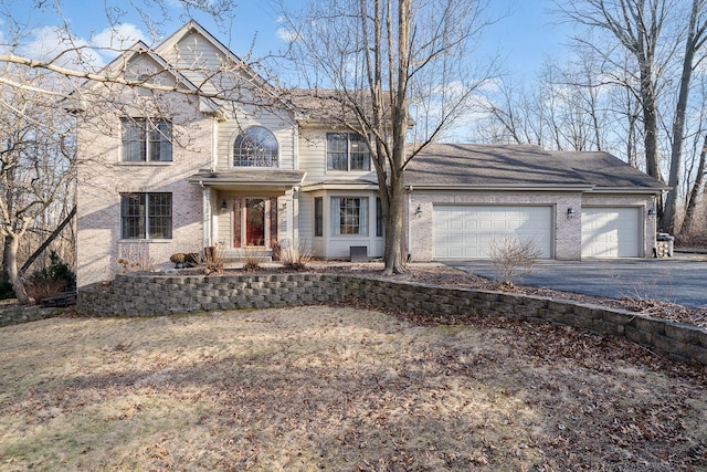 view of front of house with aphalt driveway, brick siding, and an attached garage