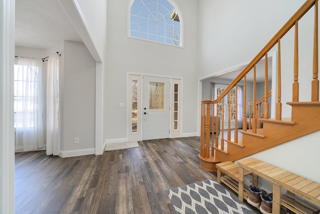 foyer entrance with a high ceiling, stairway, wood finished floors, and baseboards