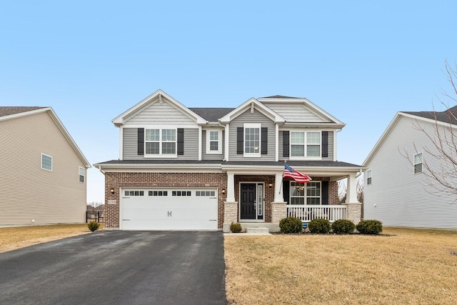 craftsman-style house featuring aphalt driveway, brick siding, a porch, a front yard, and a garage