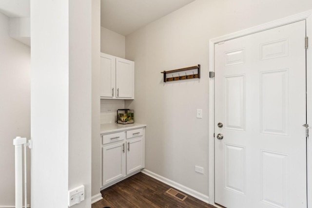 interior space with dark wood-type flooring, visible vents, and baseboards