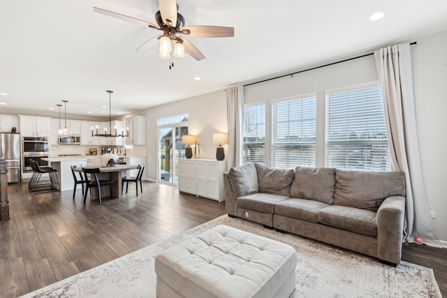 living area with recessed lighting, dark wood finished floors, and ceiling fan with notable chandelier