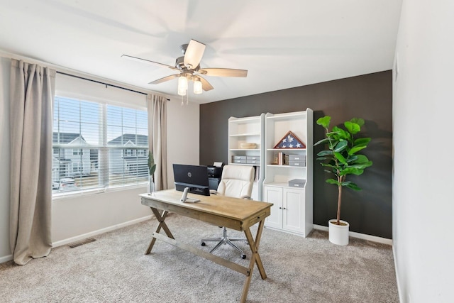 home office featuring light colored carpet, ceiling fan, visible vents, and baseboards