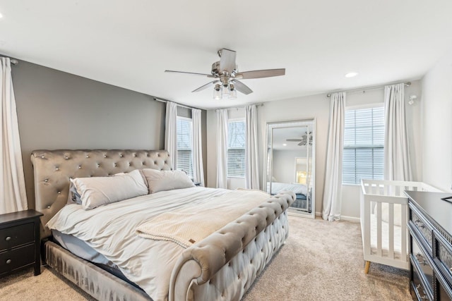 bedroom with a ceiling fan, light carpet, and baseboards