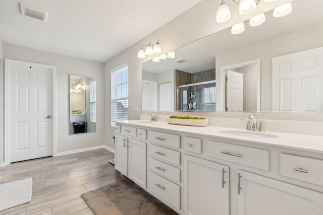 bathroom with double vanity, a stall shower, visible vents, and a sink