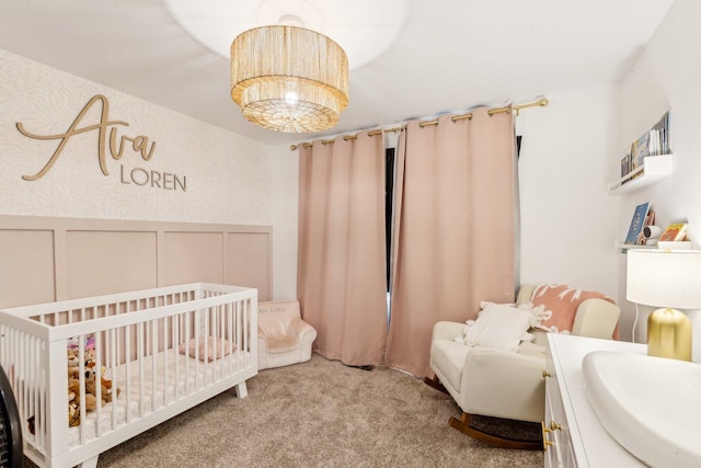 carpeted bedroom featuring a crib, a wainscoted wall, and a decorative wall