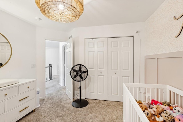 bedroom featuring a wainscoted wall, a closet, light colored carpet, and visible vents