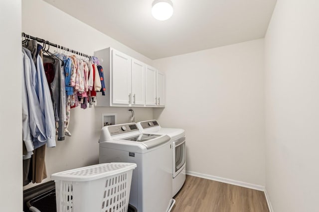 clothes washing area featuring light wood finished floors, independent washer and dryer, cabinet space, and baseboards