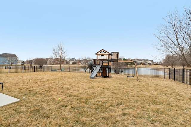 view of jungle gym featuring a water view, a lawn, and fence