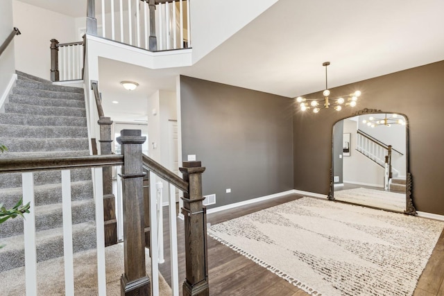 entrance foyer with arched walkways, stairway, wood finished floors, and baseboards